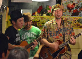 《 KATOMANZ 》Vo. A.G ナオトマン（左）Vo.Per. アッキー（中）Vo. A.G  加藤仁史（右）2010年友人の結婚パーティのため結成。主に東京近郊の酒場で南国のリズムに乗せのんきな歌を歌う合唱団。ロックテイストもかなりブレンドされているらしい。